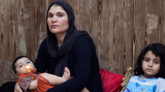 A mother holds her son, sitting next to her daughter