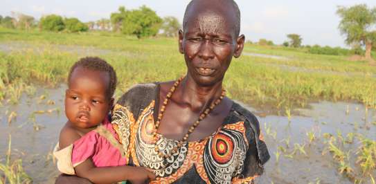 Asunta stands in her flooded farm in South Sudan