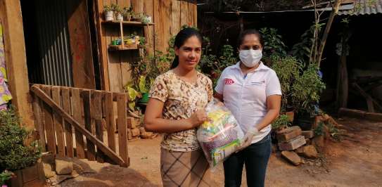 Heidy del Carmen Hernández receives a food package from Dina Gutiérrez from local partner Social Initiative for Democracy in El Salvador.