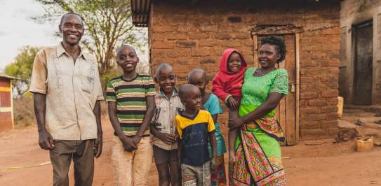 Faith Muvili poses with her family (husband and 5 children) in front of their house.