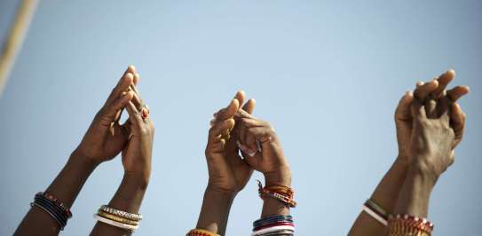 Image shows three pairs of arms reaching to the sky with hands clasped in pairs linking in a chain