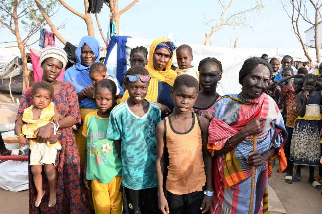 Martha pictured with her family in front of her makeshift shelter in the transit centre, Renk. Credit: Silvano Yokwe/Christian Aid