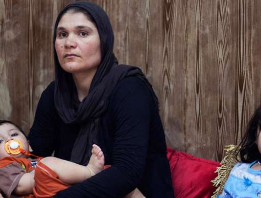 A mother holds her son, sitting next to her daughter