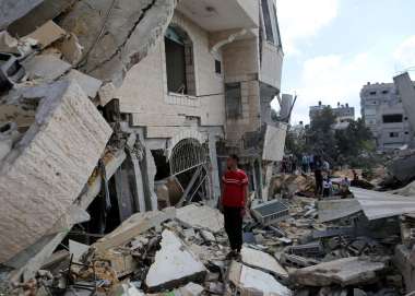 A man stands amongst the rubble of a destroyed building